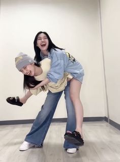 two young women are dancing on the floor