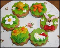 four decorated cupcakes sitting on top of a white plate