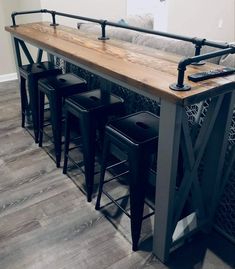 a wooden table with four stools next to it and a couch in the background