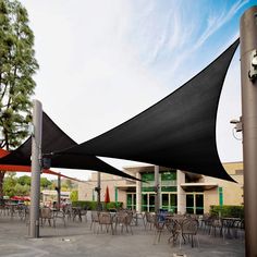 an outdoor dining area with tables and chairs covered in black shade cloths on poles