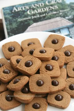 a white plate topped with lots of cookies on top of a table next to a book