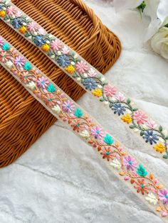 two different colored flowers are on the side of a wicker basket next to some white flowers