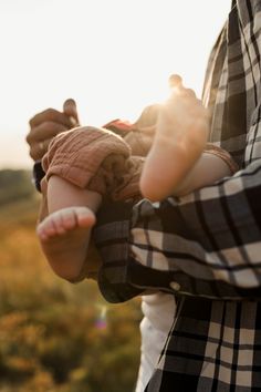 a woman holding a baby in her arms with the sun shining on her face and hands