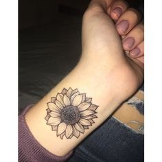 a woman's arm with a sunflower tattoo on the left side of her wrist