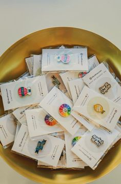 a gold bowl filled with lots of different types of pins and tags on top of each other