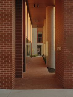 an empty hallway between two buildings with red bricks