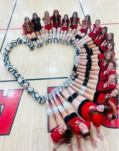 a group of cheerleaders standing in a heart shape on a basketball court with their hands together