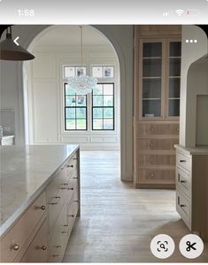 a kitchen with an arched doorway leading into the dining room and living room, as well as a white marble counter top