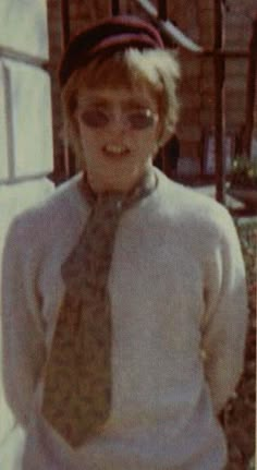 an old photo of a young boy wearing glasses and a tie with his hands in his pockets