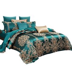 a bed covered in teal and gold comforter with pillows on top of it