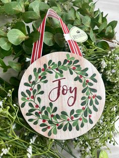 a wooden ornament hanging from a wreath with the word joy painted on it