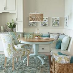 a dining room table with blue chairs and pillows on top of it in front of a white cabinet