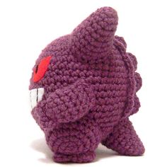 a purple crocheted stuffed animal with red eyes