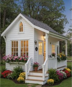 a small white house with flowers on the porch and steps leading up to the front door