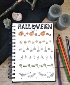 a notebook with halloween doodles on it next to some colored pencils and rocks