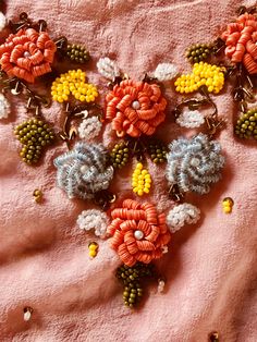 a close up of a necklace on a pink cloth with beads and flowers attached to it