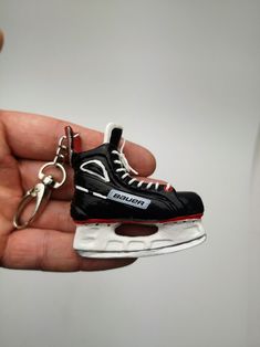 a hand holding a black and white sneaker keychain with a pair of shoes on it