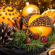 an arrangement of oranges, pine cones and other holiday decorations on a wooden table