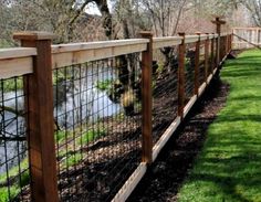 a wooden fence next to a river in the grass