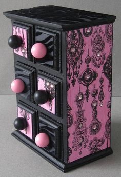 a pink and black jewelry box with three drawers on each side, decorated with ornate designs