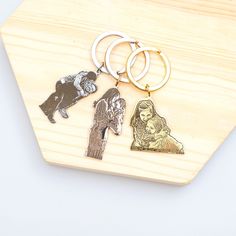 three different key chains on top of a wooden board with an image of jesus and mary