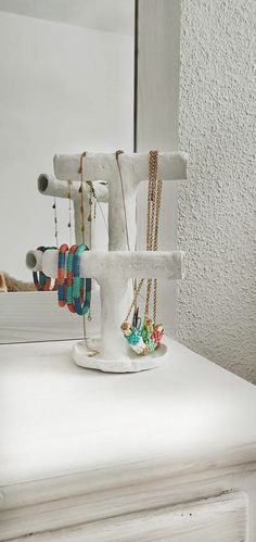 a white table with jewelry on it and a mirror in the backgroung