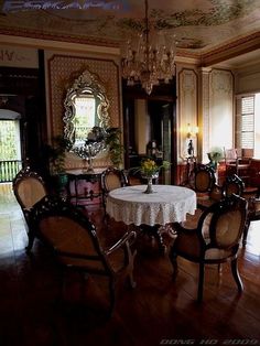 an ornate dining room with chandelier, table and chairs in front of large windows