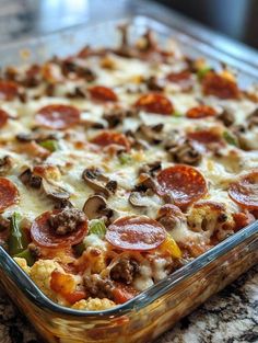 a pizza casserole with pepperoni, mushrooms and green peppers in a glass dish