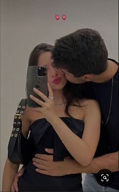 a man and woman taking a selfie in front of a mirror with their cell phone