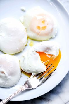 three fried eggs on a white plate with a fork