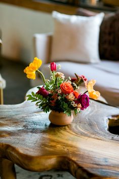 a wooden table topped with a vase filled with lots of flowers on top of it