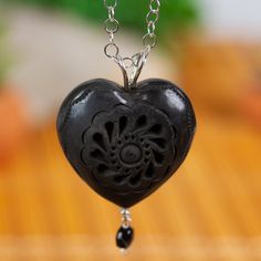 Barro negro or black clay is a distinctly Oaxacan crafting tradition that dates back centuries. Mariana Barranco in Mexico creates this gorgeous necklace with a heart-shaped barro negro pendant incised with small petal motifs. The pendant graces a sterling silver rolo chain stationed with glossy black crystal beads. Artisan Black Carved Jewelry, Adjustable Black Carved Necklace, Black Bohemian Fair Trade Jewelry, Bohemian Black Fair Trade Jewelry, Artisan Black Pendant Jewelry, Artisan Heart Beads Pendant Necklace, Carved Heart Shaped Jewelry Gift, Carved Heart-shaped Jewelry For Gift, Heart Shaped Carved Jewelry Gift