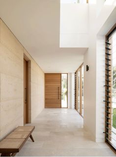 an empty hallway with a bench and wine rack on the wall next to it's doors