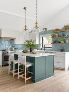 a kitchen with blue and white cabinets, wood flooring and an island in the middle