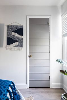 a bedroom with white walls and blue blankets on the bed, next to a door