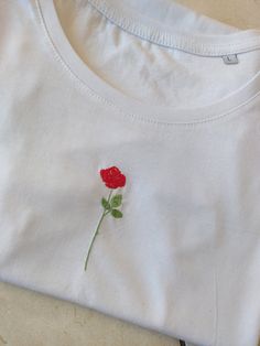 a white t - shirt with a red rose embroidered on it