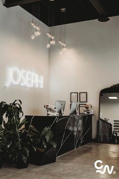 the interior of a hair salon with plants and lights hanging from the ceiling above it