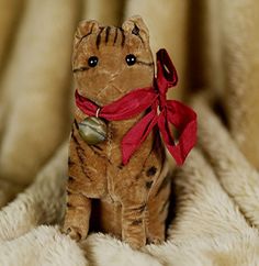 a small stuffed cat with a red ribbon around its neck