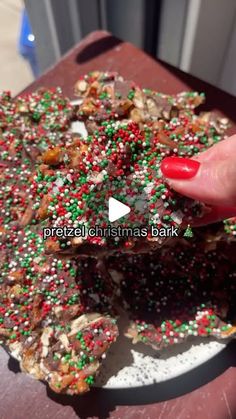 a person holding up a piece of food with sprinkles and nuts on it