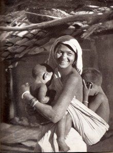 an old black and white photo of a woman holding a baby in her arms with two other men nearby