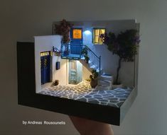 a doll house is being held up by someone's hand with the door open