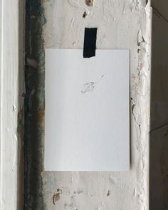 a piece of paper hanging on the side of a wall with some paint peeling off it