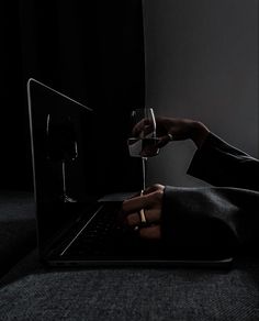 a person holding a wine glass while using a laptop