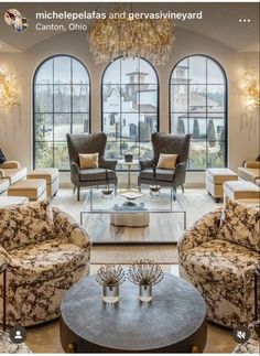 a living room filled with lots of furniture next to large windows and chandelier