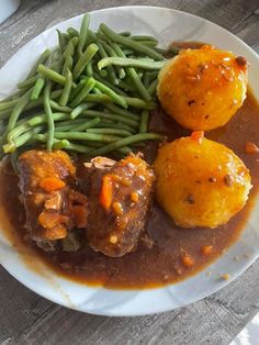 a white plate topped with meatballs and green beans