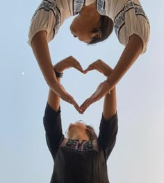 two women making a heart with their hands in the shape of a heart on top of each other