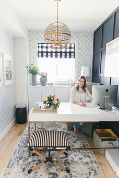 a woman walking through a living room with a rug on the floor and a desk in front of her