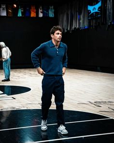 a man standing on top of a basketball court next to another man in the background