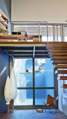 an indoor swimming pool with stairs leading up to the upper floor and above it is a wooden staircase