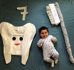 a baby laying on top of a bed next to a toothbrush and other items